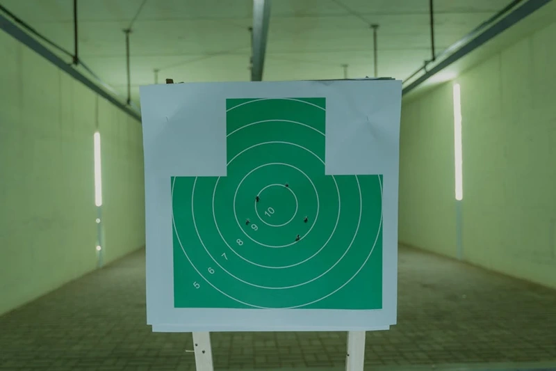 Bullet-riddled green target in shooting range.